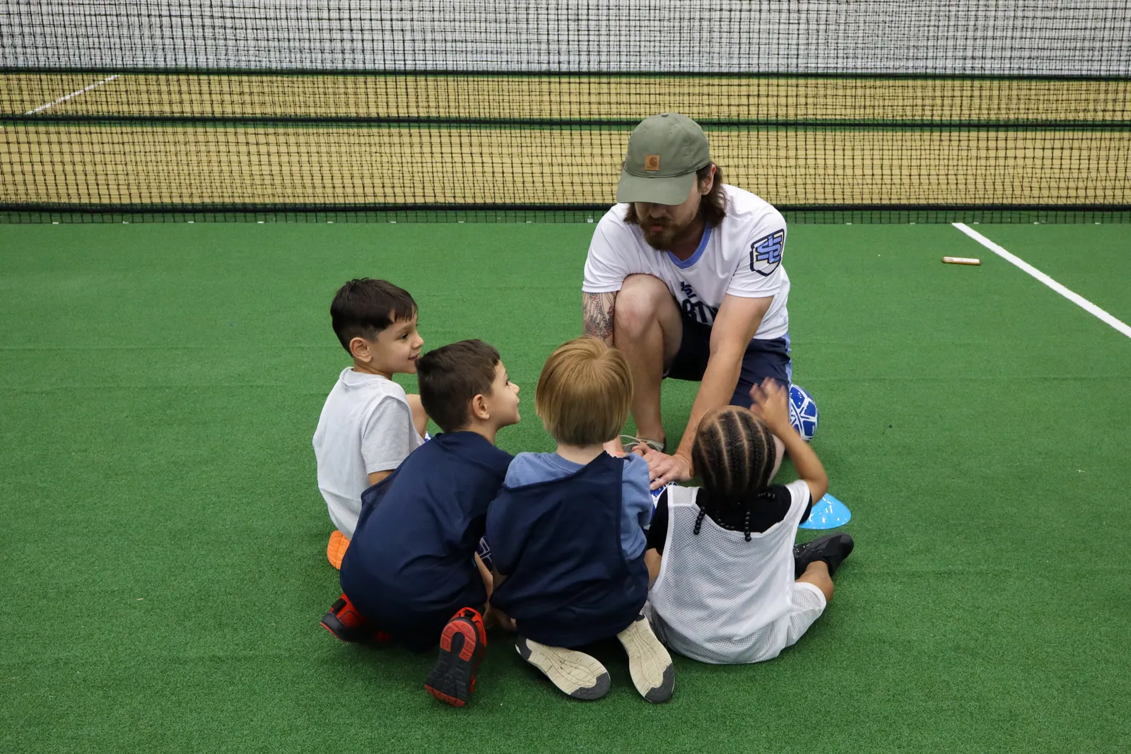 Coach kneeling at kid level talking to a small group on the field